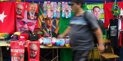 Ambulante com toalhas de Lula e Fl&aacute;vio Bolsonaro a venda na rua Siqueira Campos, em Copacabana, zona sul do Rio de Janeiro. Foto: Pedro Kirilos/Estad&atilde;o / Estad&atilde;o